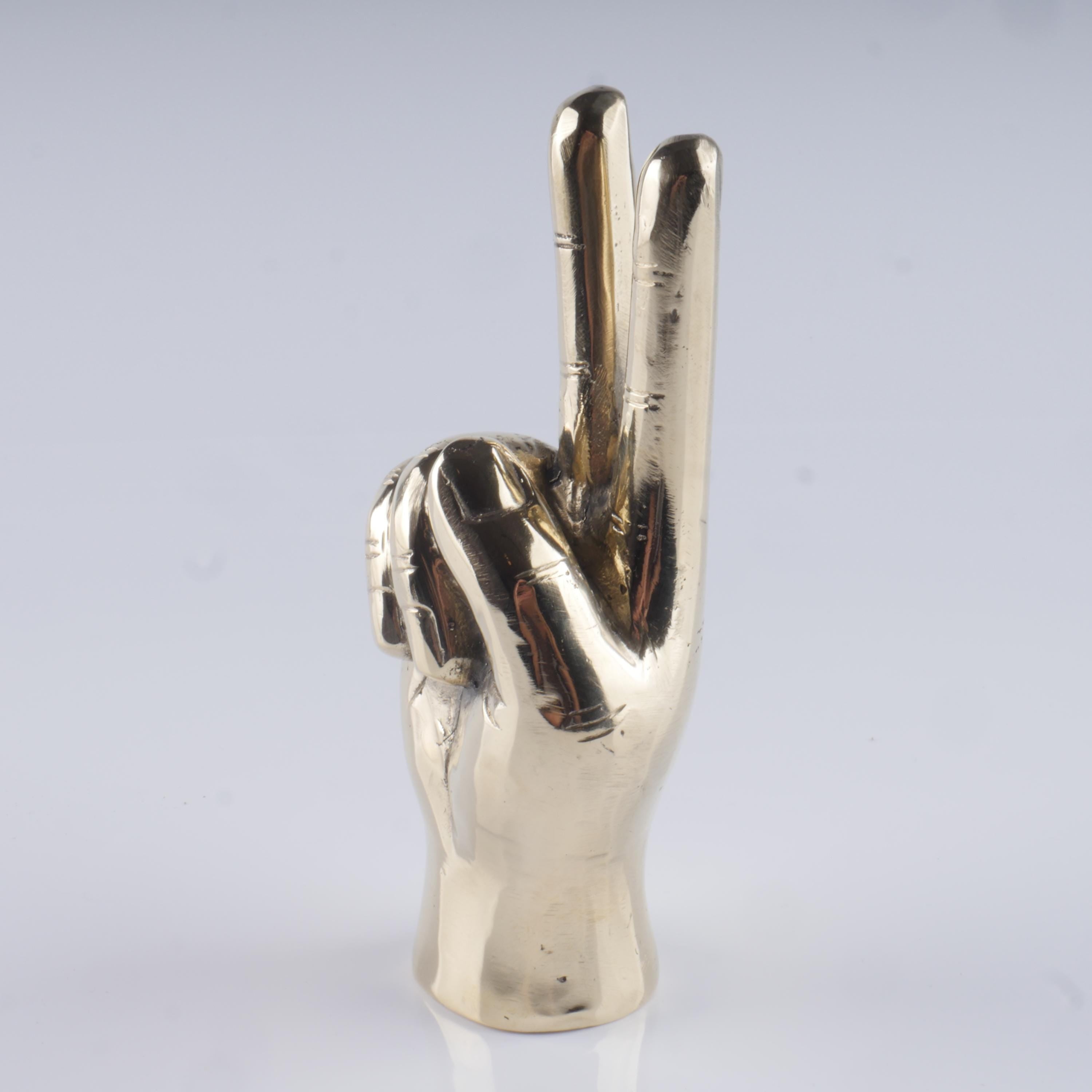 a silver metal sculpture of a hand making a peace sign