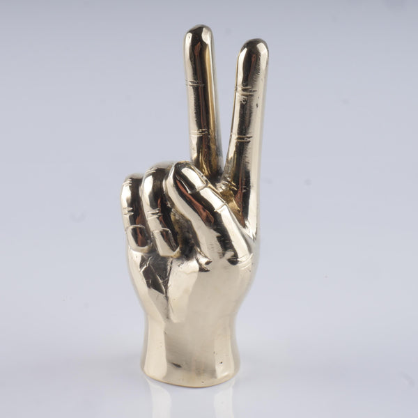 a silver metal peace sign on a white surface