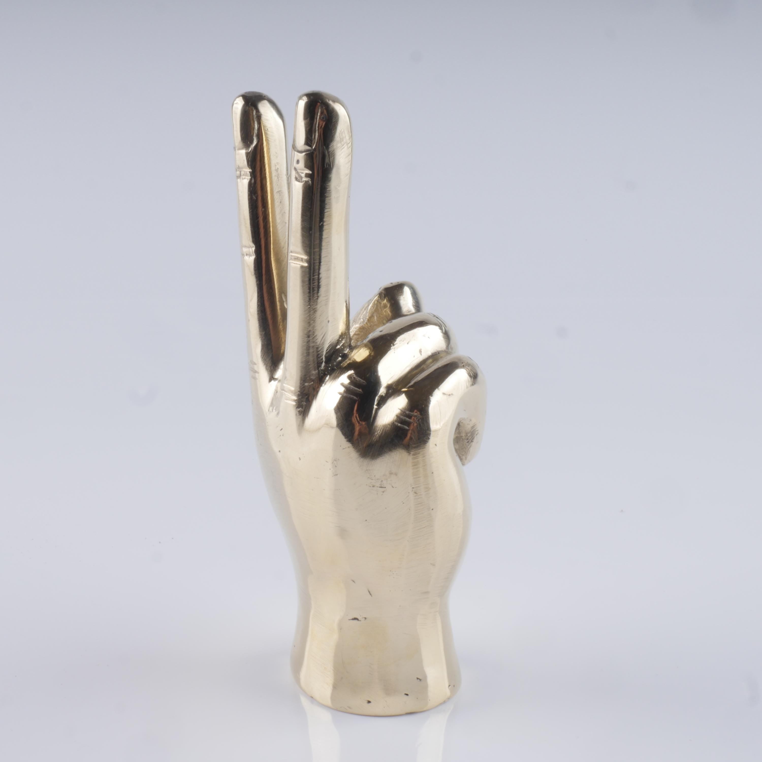 a silver metal sculpture of a hand making a peace sign