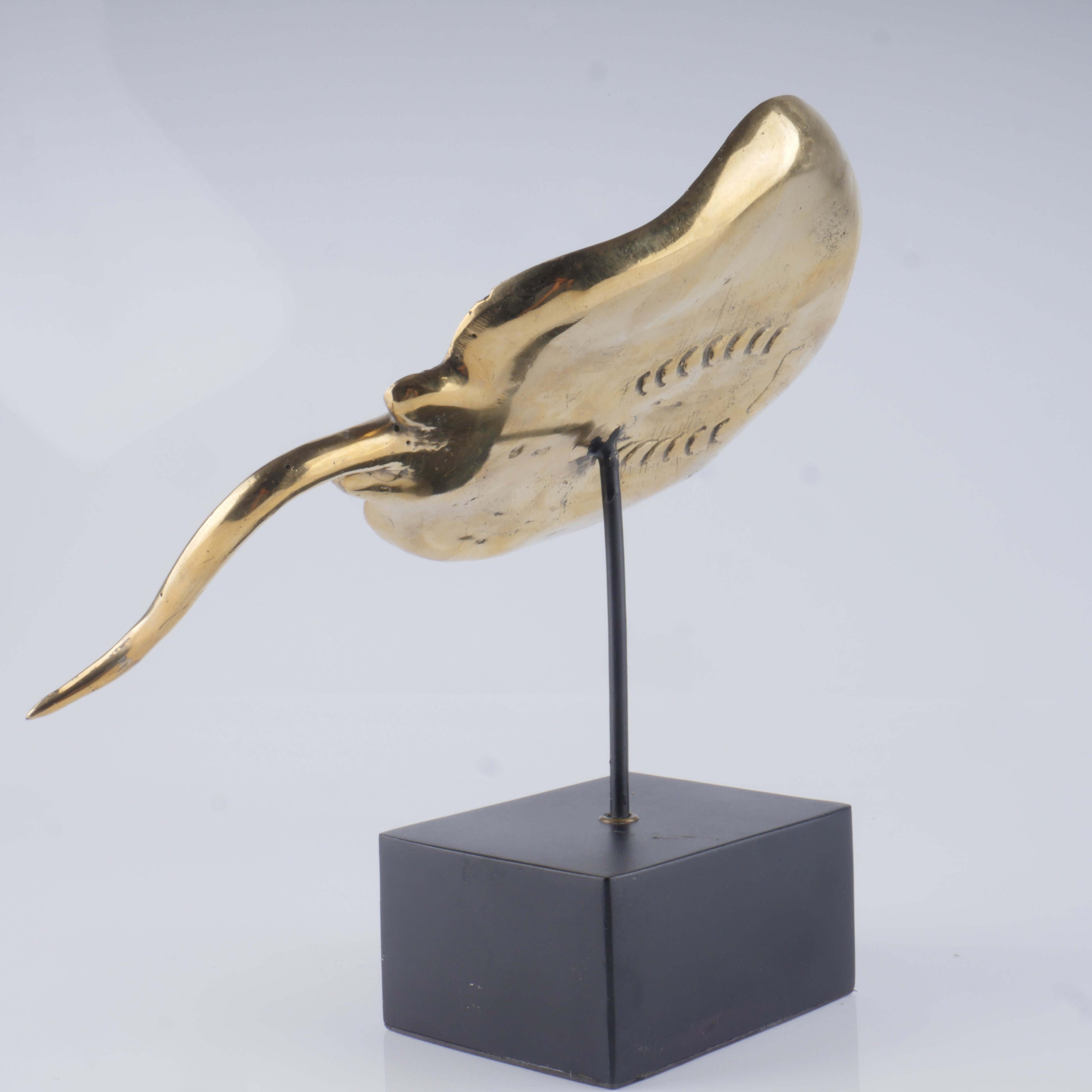 a gold sculpture of a bird on a black stand