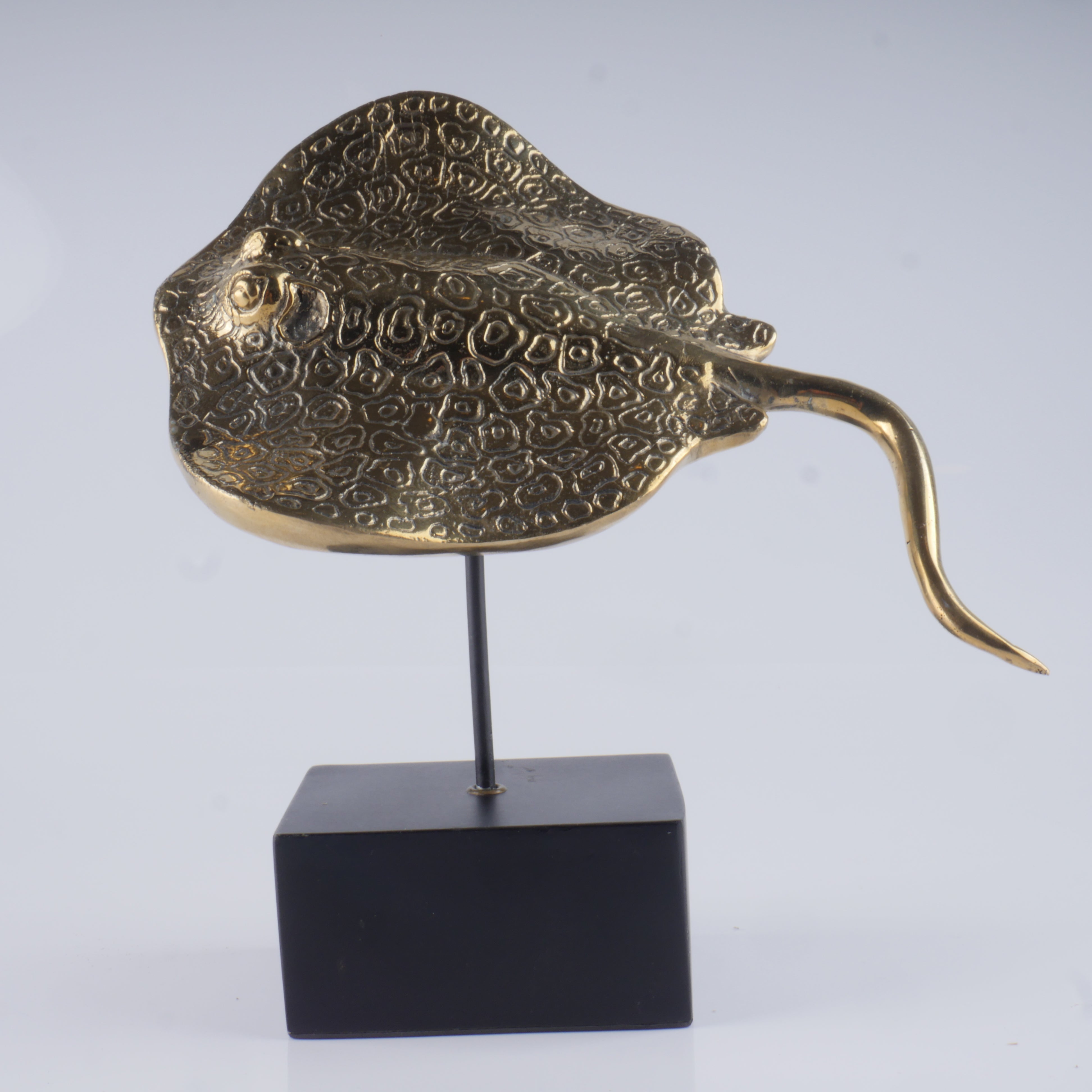 a gold sculpture of a fish on a black stand