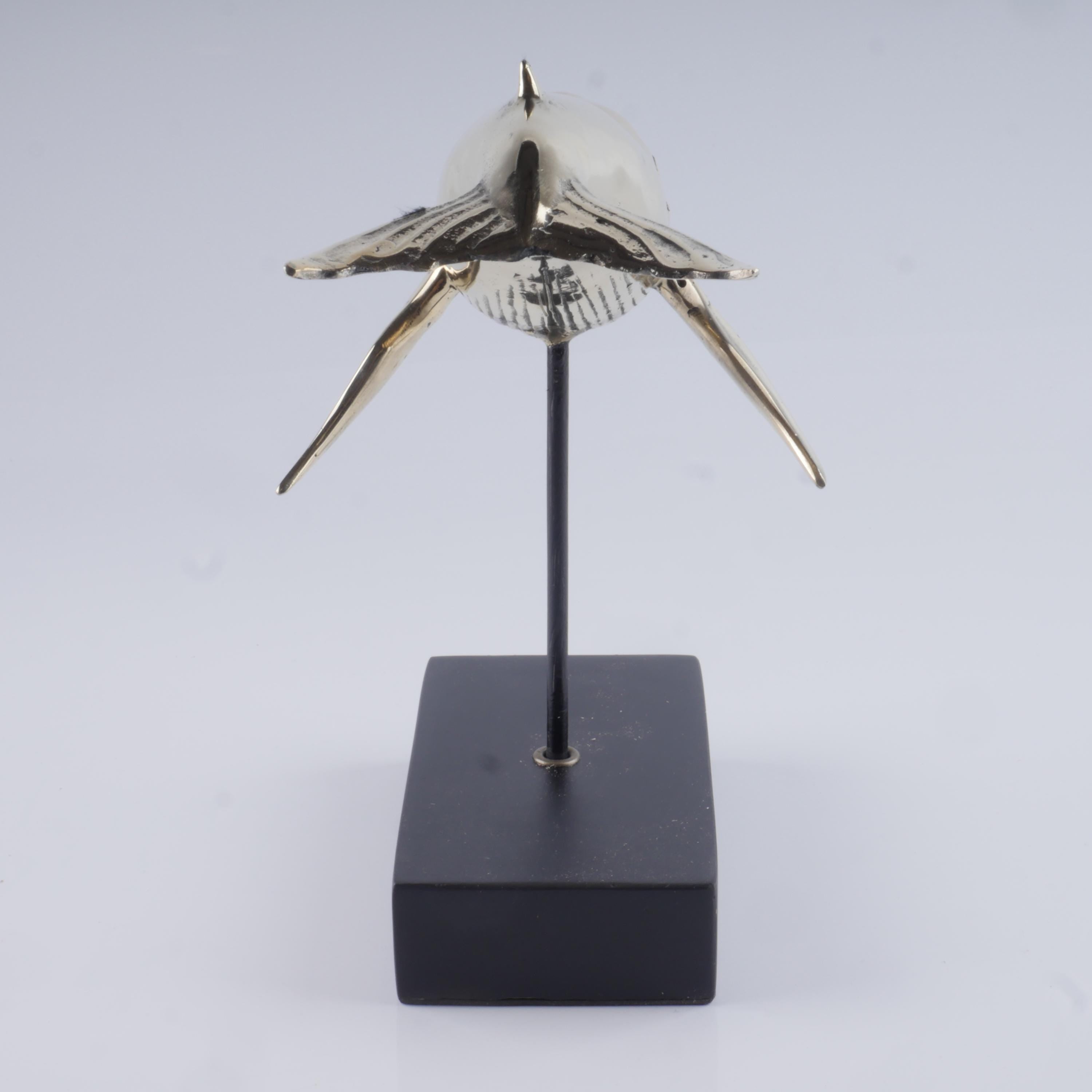 Elegant cast golden brass humpback whale sculpture with detailed features.