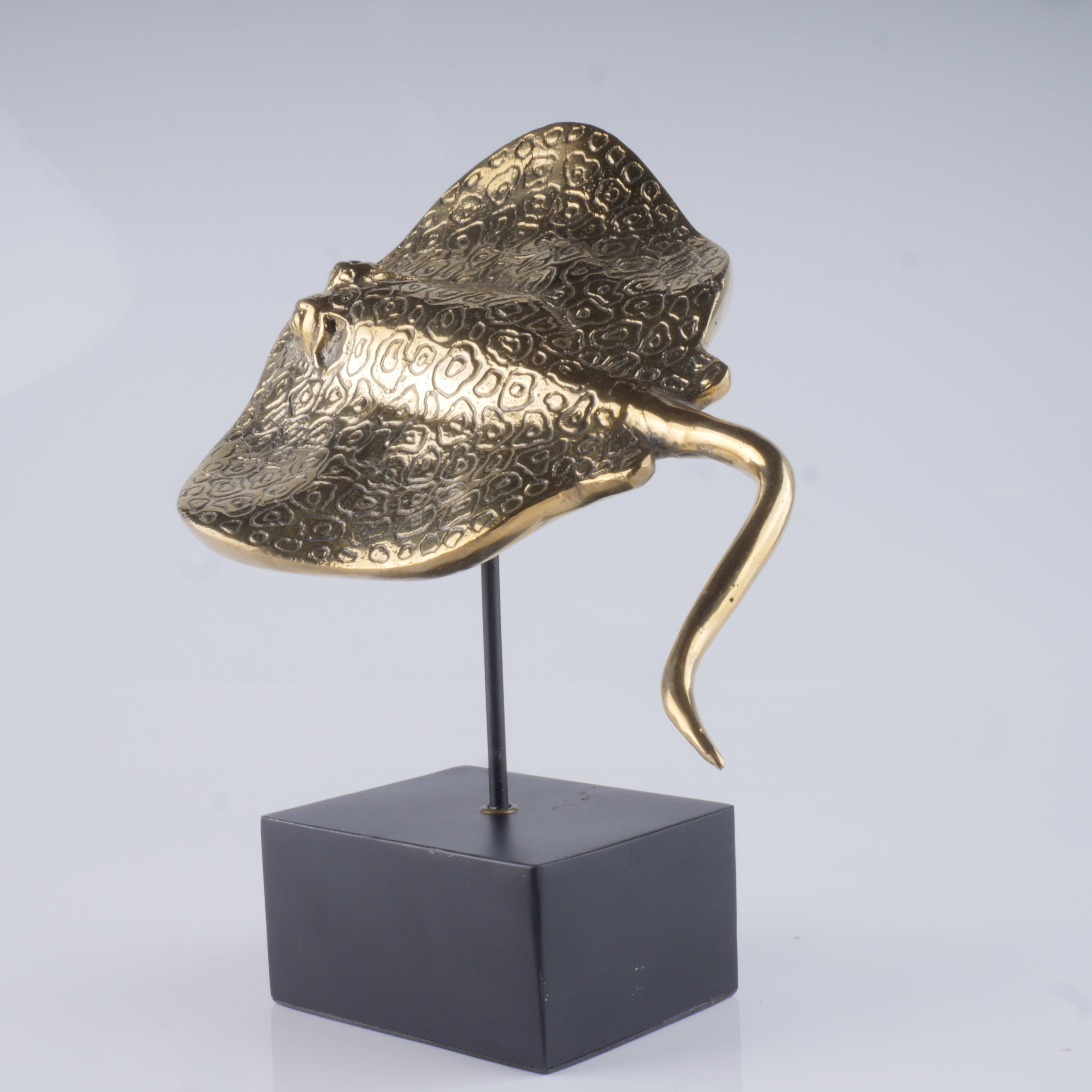 a gold sculpture of a hat on a black stand