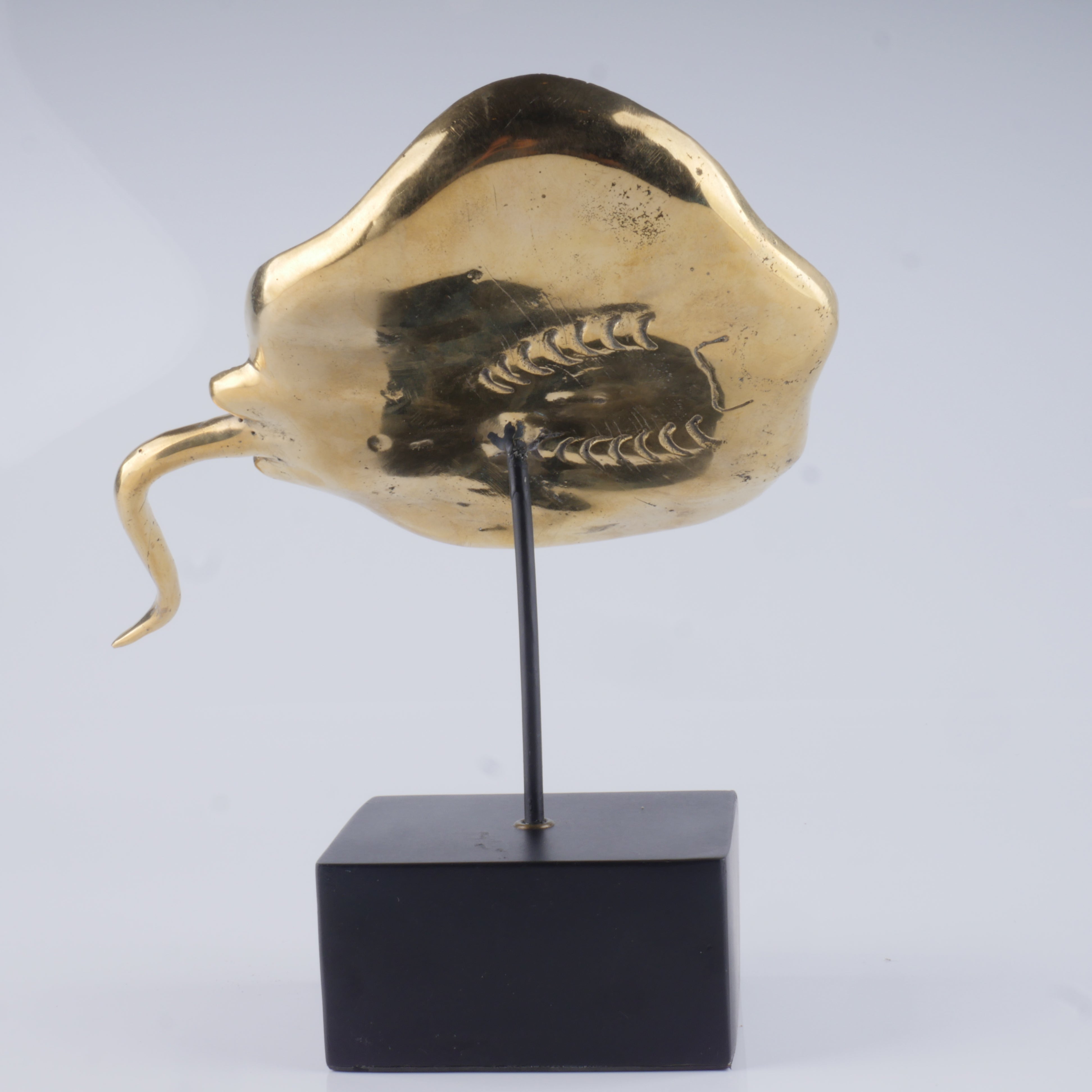a gold sculpture of a fish on a black stand