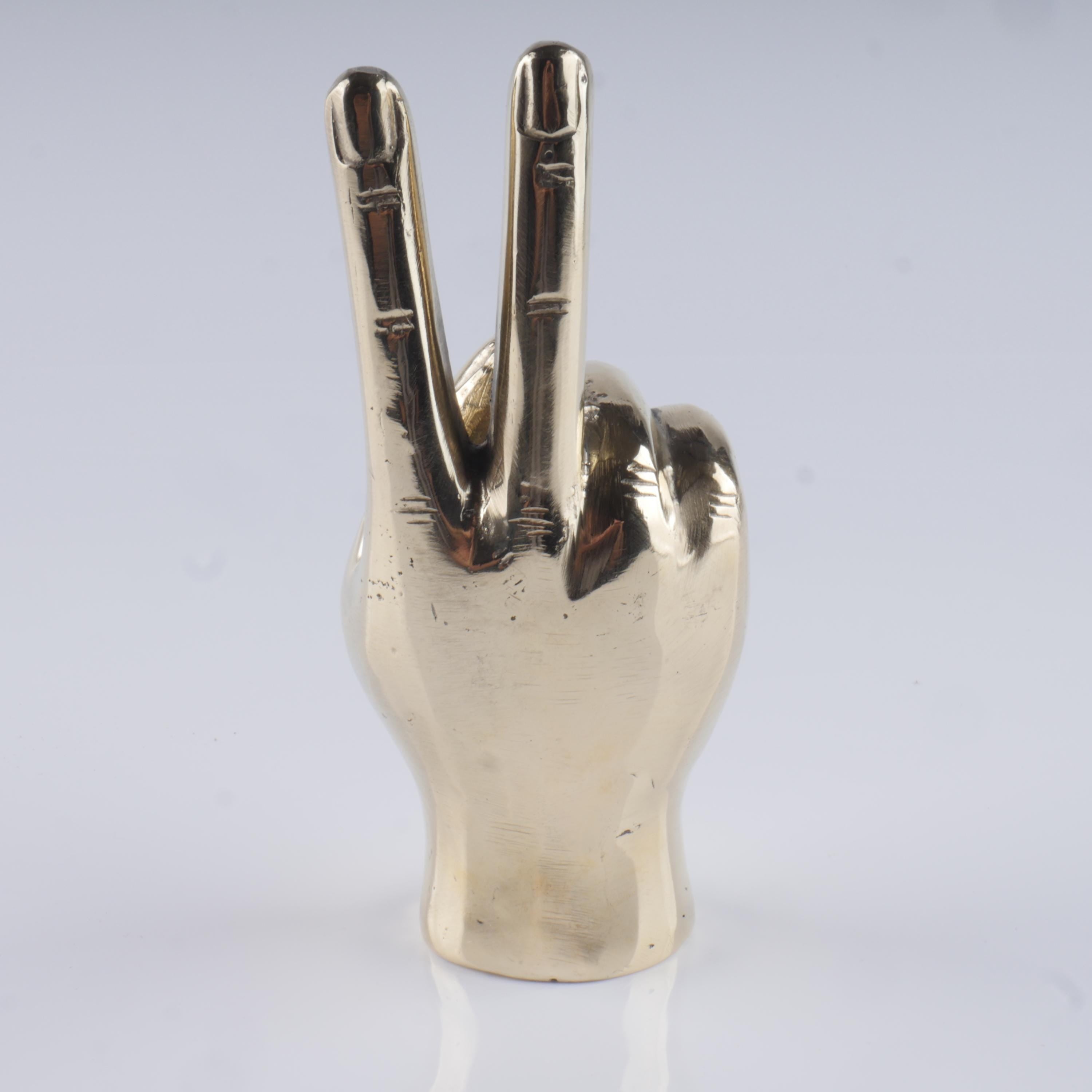 a silver metal peace sign on a white surface