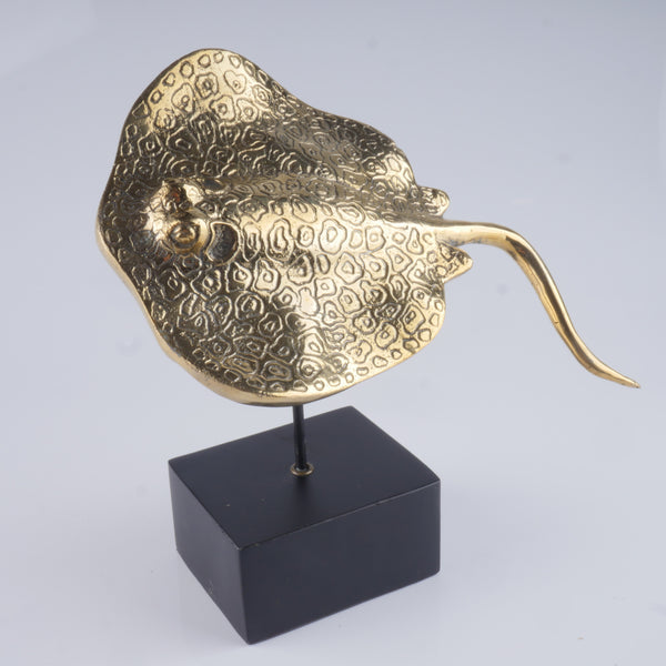 a gold sculpture of a bird on a black stand