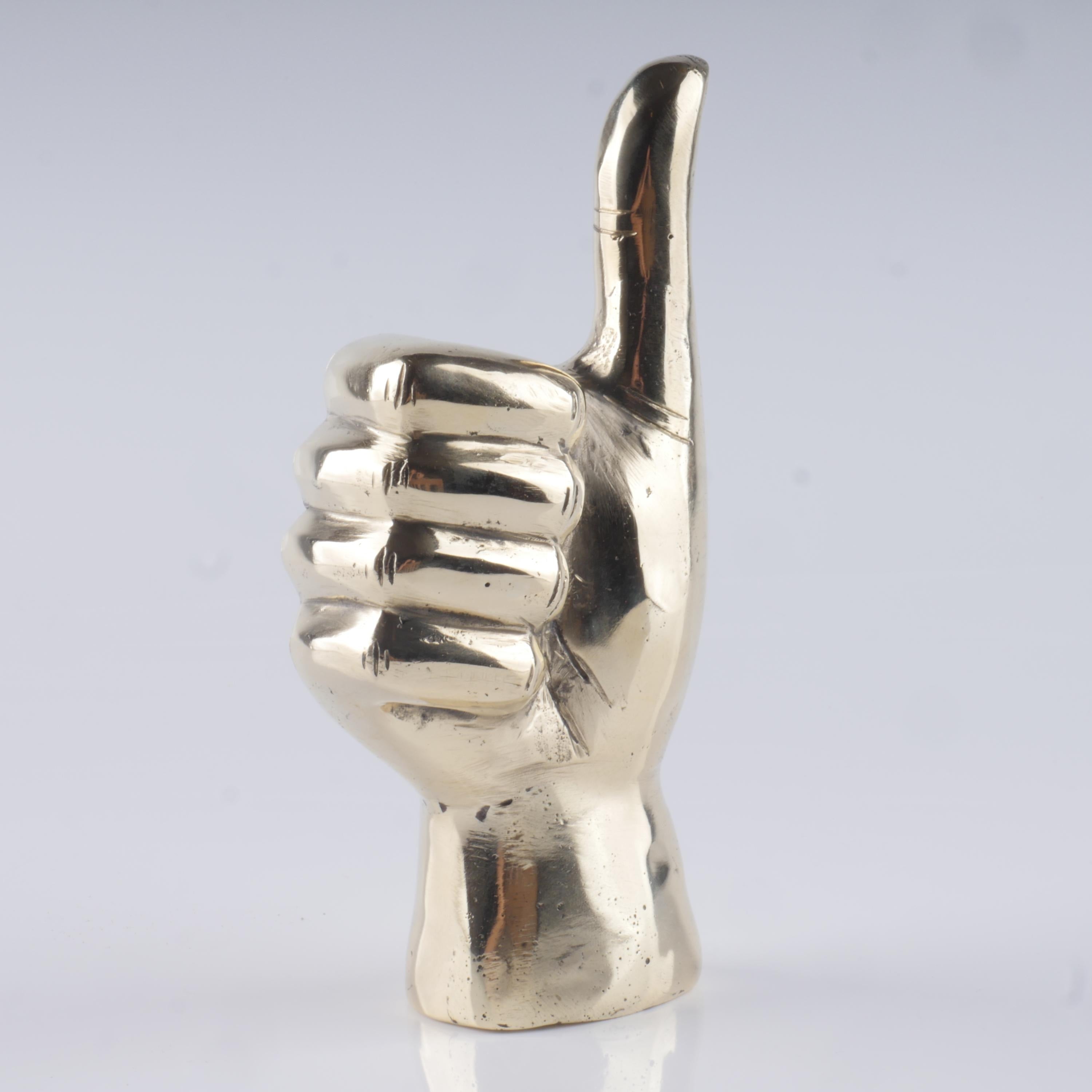 a silver metal statue of a hand giving a thumbs up