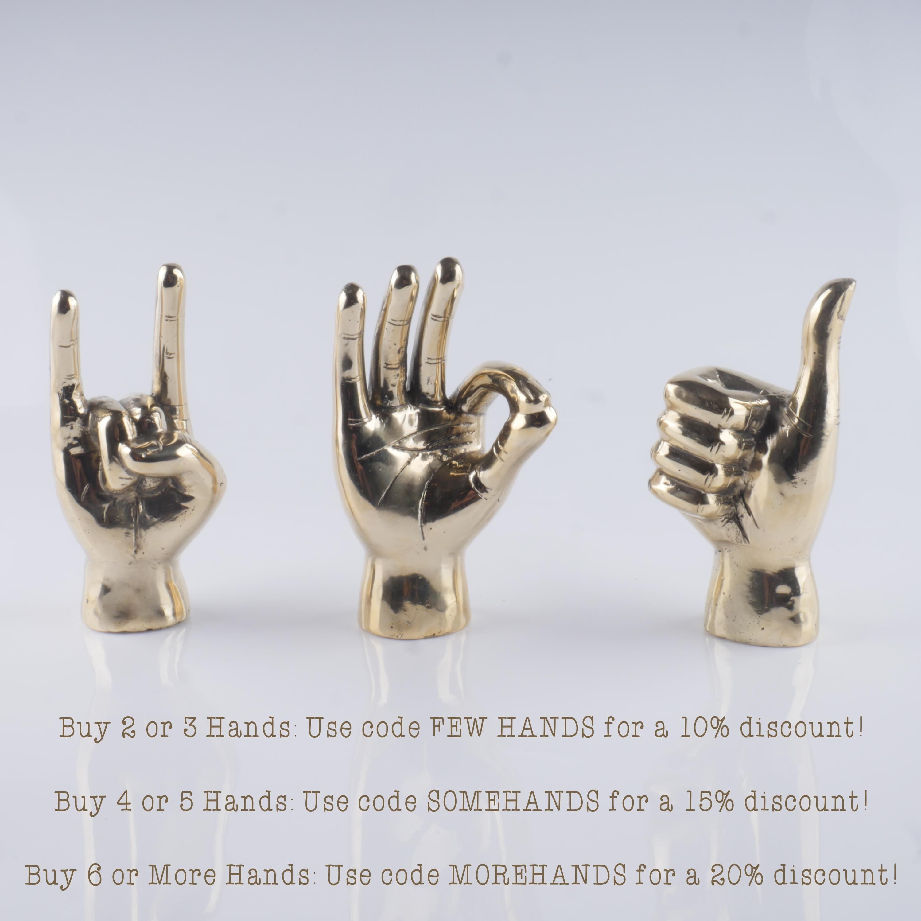 a group of three gold colored metal hand sculptures