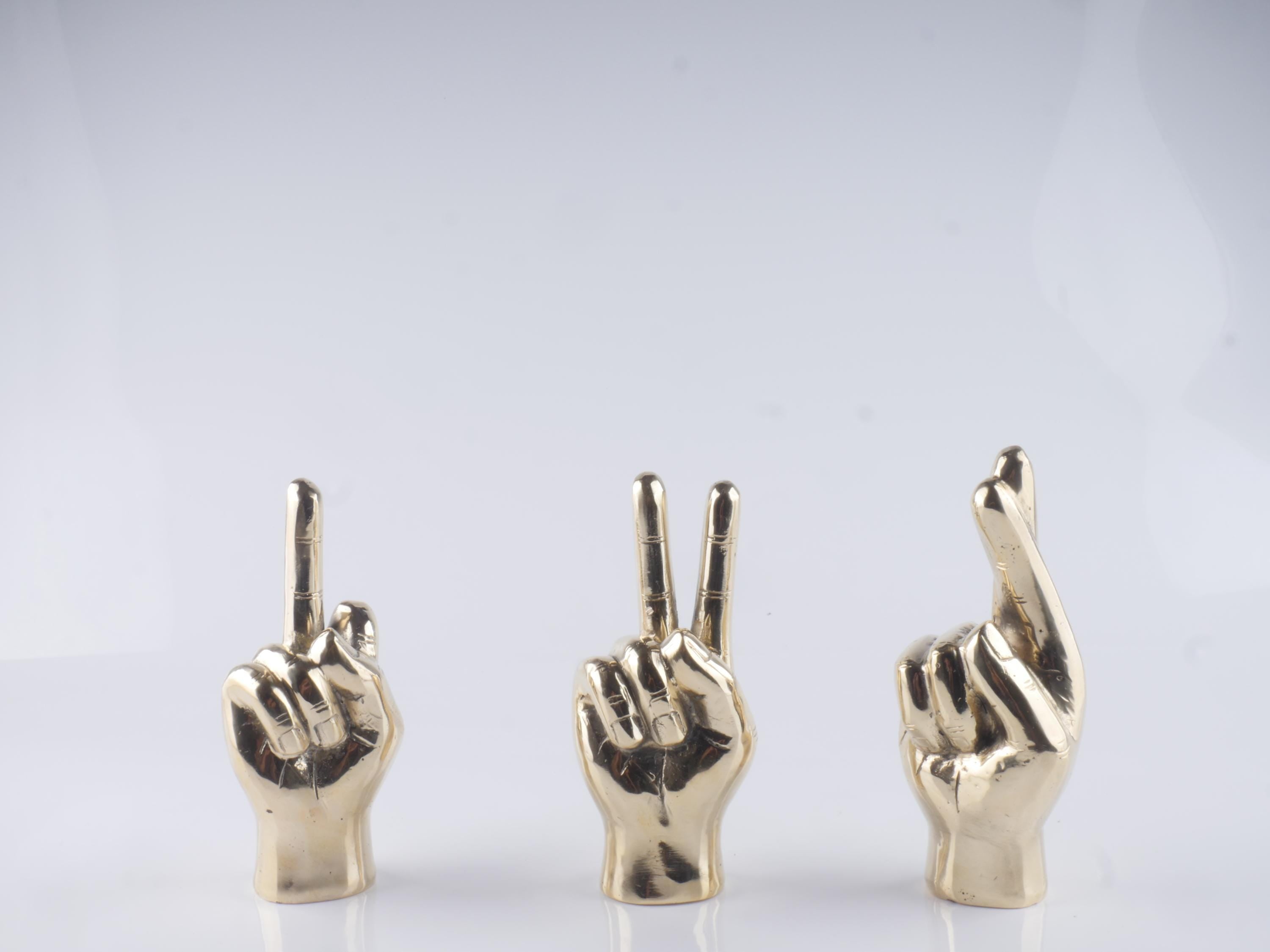 a group of three gold colored hand gestures